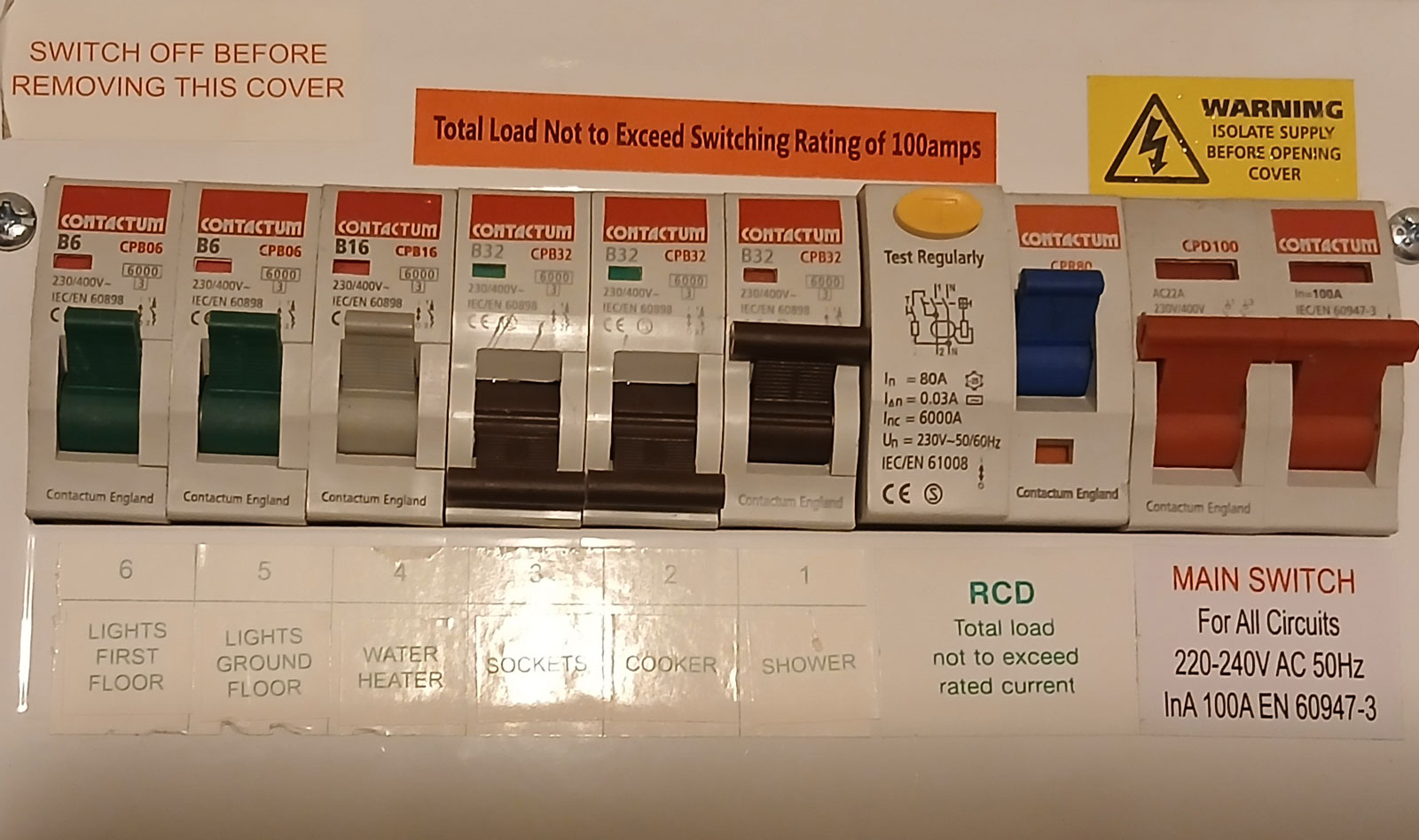Domestic consumer unit showing legacy electrical configuration with multiple final circuits grouped without individual RCD protection. The sockets serving both ground and first floor are supplied via a single breaker, with shower and cooker circuits routed adjacent, demonstrating outdated circuit segregation and elevated fire and shock risk where water ingress and damp conditions were present elsewhere in the property.